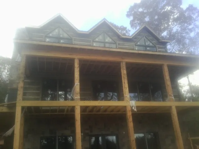 Dormers and porch framing on a large log home under construction — Roof Coating work by our crew in Altamont