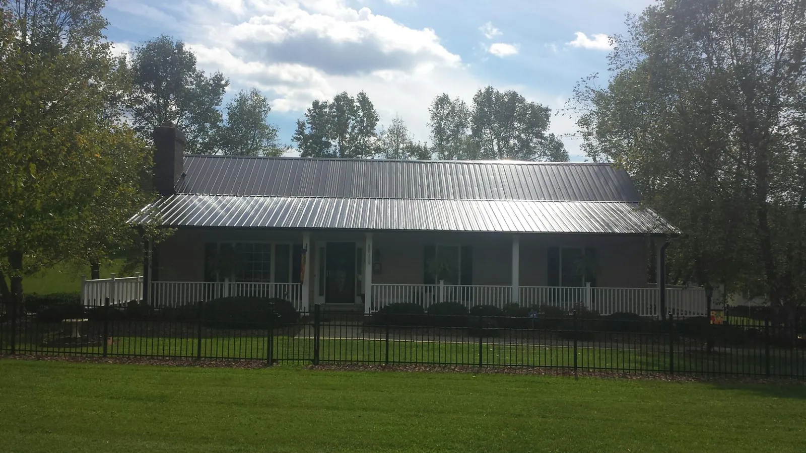 Gray metal roof on a brick ranch with a full width front porch — Gutter Guard Installation work by our crew in Altamont